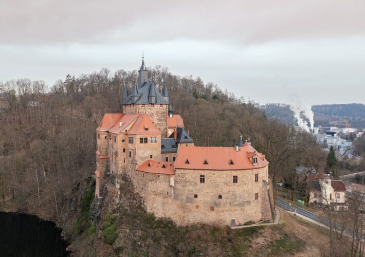 Burg Kriebstein auf einem bewaldeten Felsvorsprung über der Zschopau, umgeben von Laubwald, mit Blick ins Tal und Richtung Waldheim