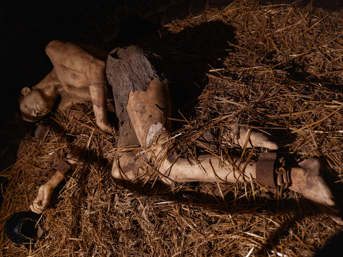 Gefesselter Gefangener liegt im dunklen Kerker auf Stroh, angekettet in der Düsternis