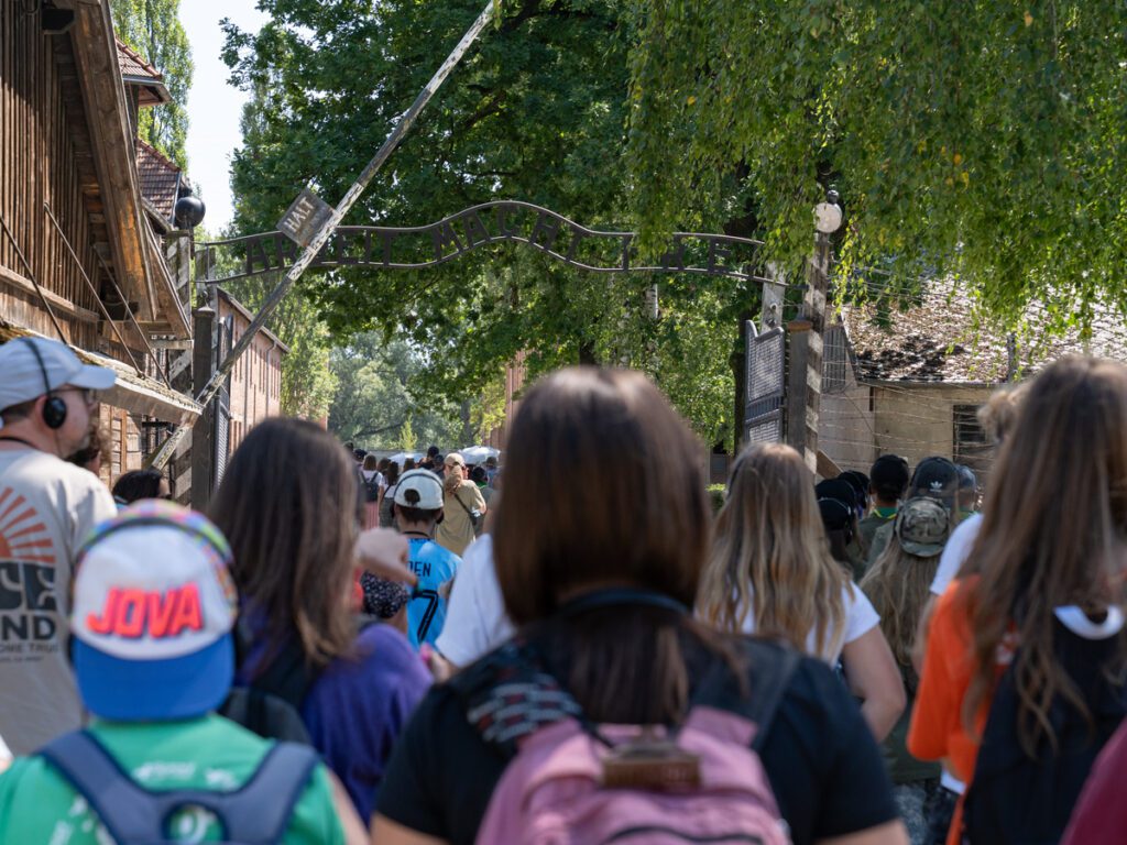 Besuchergruppe betritt Auschwitz I durch das Tor mit der Aufschrift „Arbeit macht frei“
