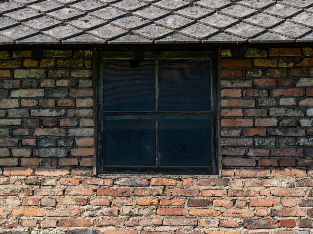 Im Schatten, einfaches Fenster einer Frauenbaracke in Auschwitz-Birkenau