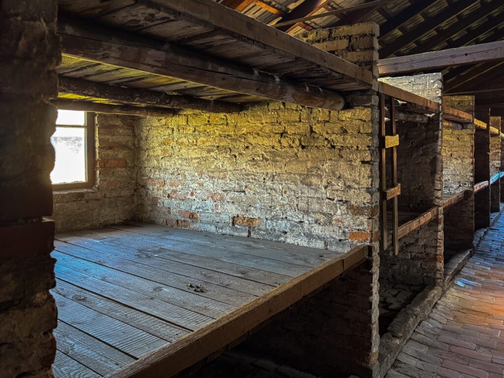 Mehrstöckige Holzpritschen im Inneren einer Frauenbaracke in Auschwitz-Birkenau
