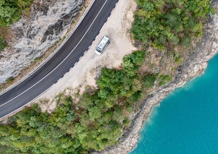 Camper an Küstenstraße mit türkisfarbenem Wasser aus der Vogelperspektive
