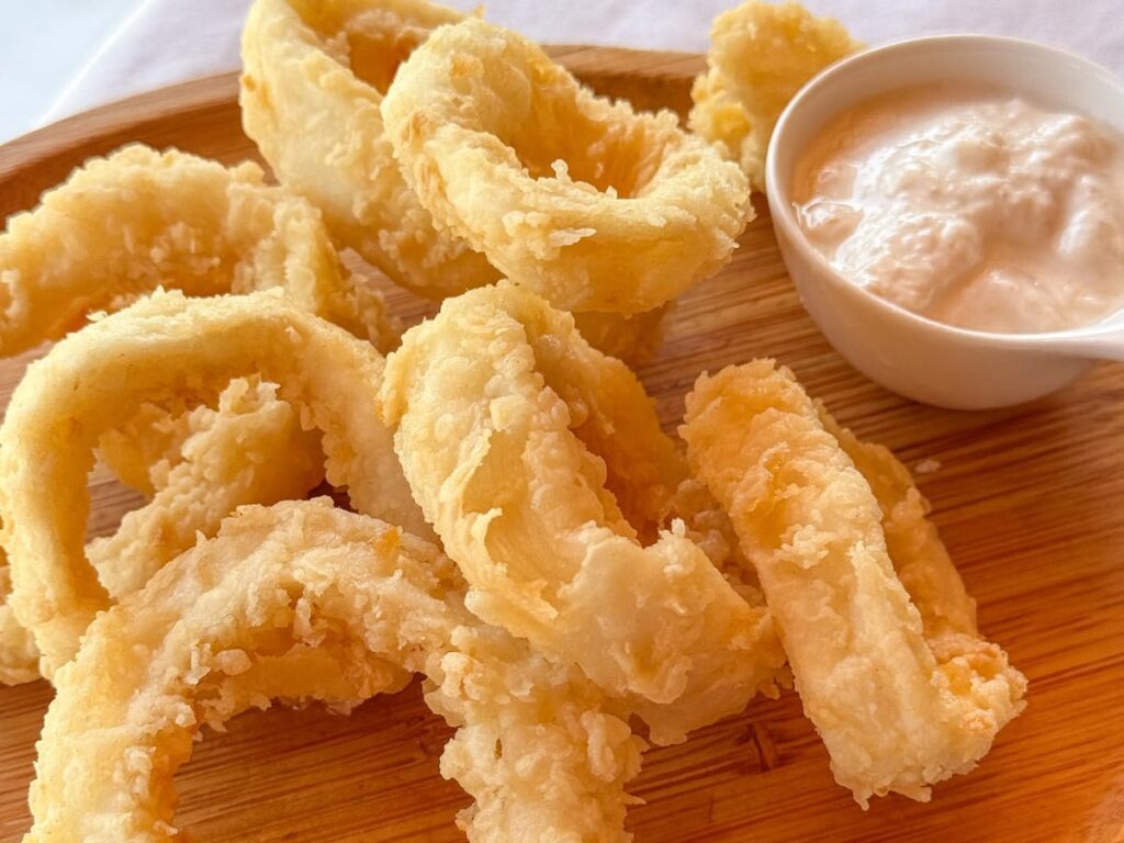 Frittierte Calamari-Ringe mit Dip auf einem Holzbrett serviert
