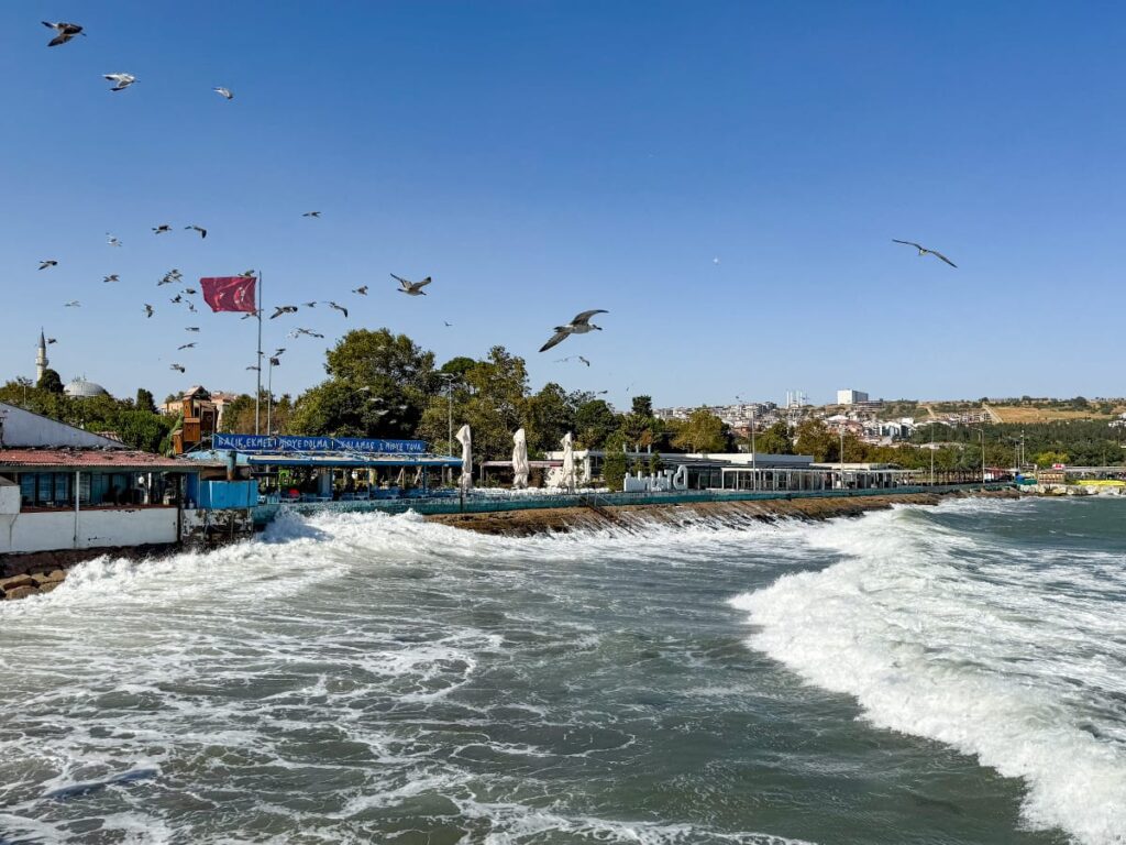 Wellen schlagen gegen die Küste, Möwen fliegen über Restaurants und eine türkische Fahne