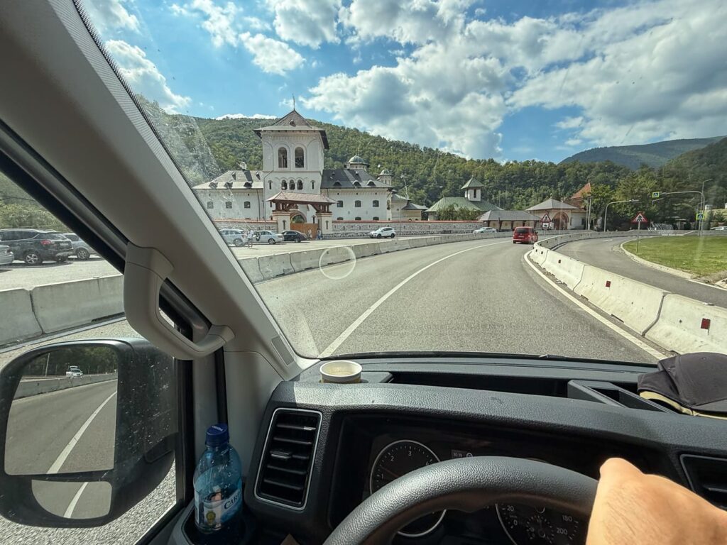 Blick aus dem Camper auf das Lainici-Kloster an der E79, umgeben von Bergen und Wäldern.