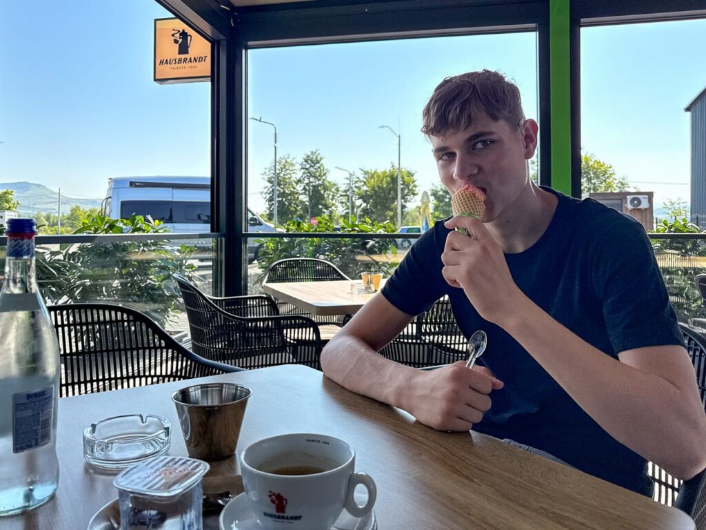 Mein Sohn genießt am Morgen ein Eis zum Frühstück, während ein Kaffee auf dem Tisch wartet.