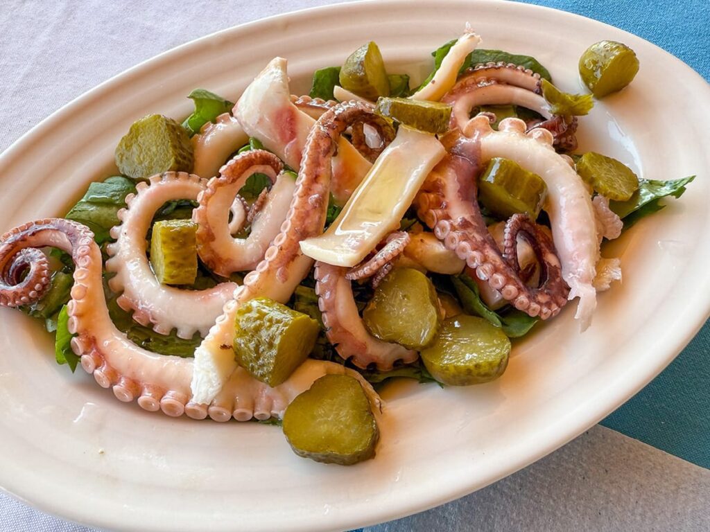 Oktopus-Salat mit Gurkenstücken und frischem Gemüse auf einem Teller