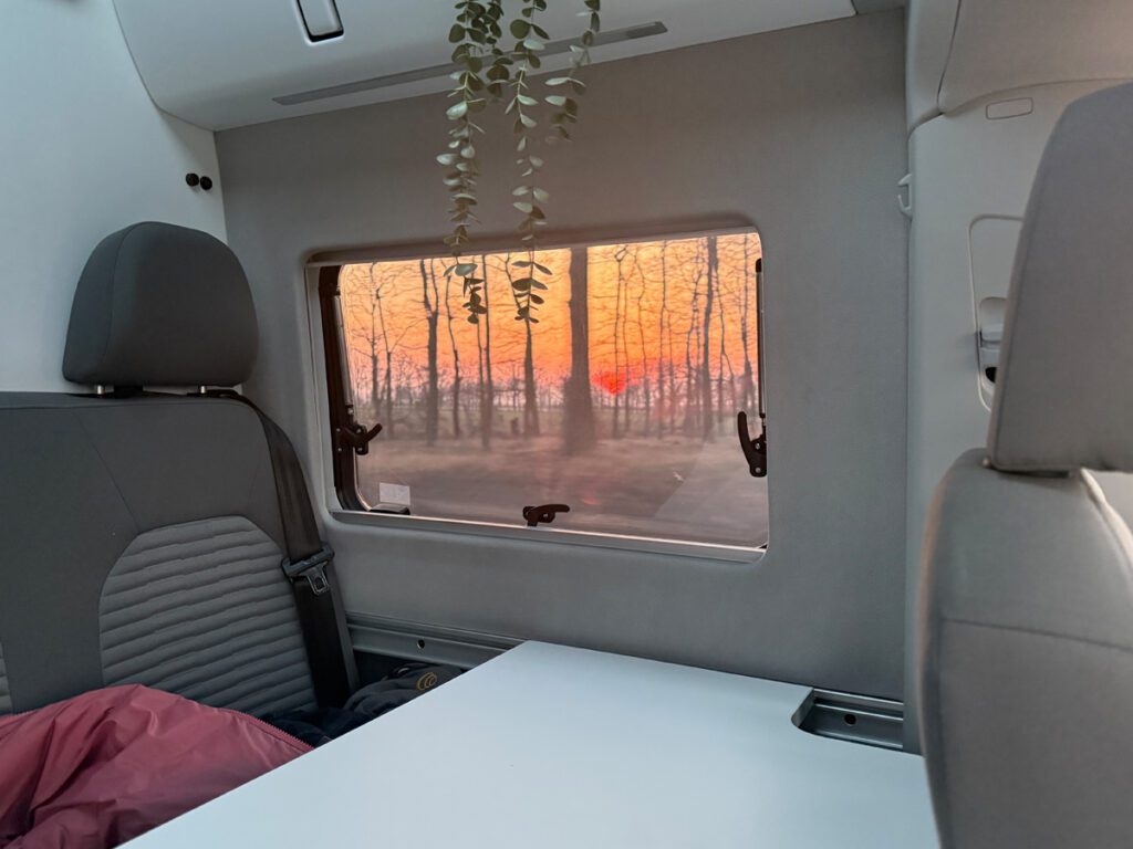 Sonnenuntergang durch das Fenster des VW Grand California