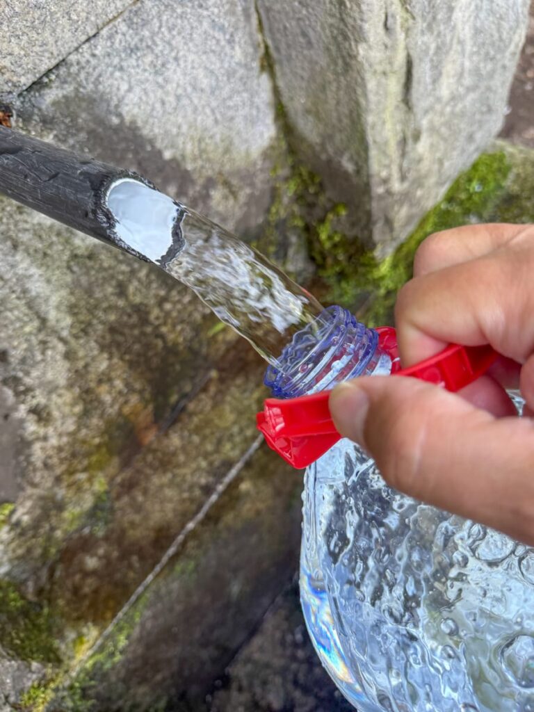 Wasser in eine Plastikflasche aus einer Gebirgsquelle füllen