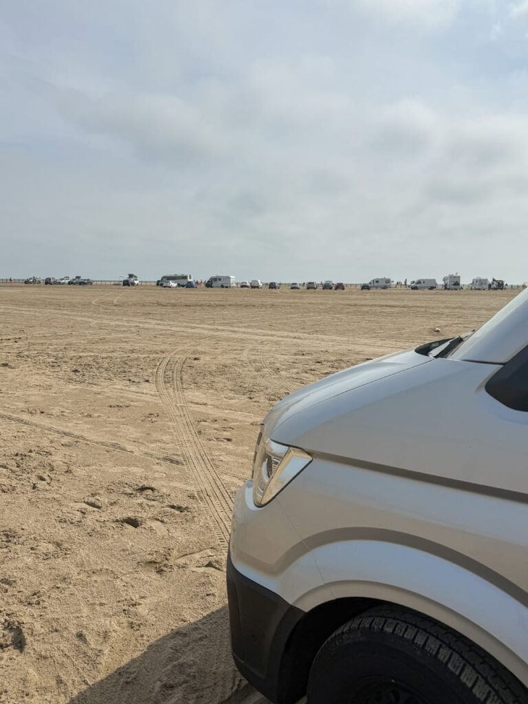 Camper und Autos stehen verstreut auf der weiten Sandfläche des Strandes von Salin-de-Giraud