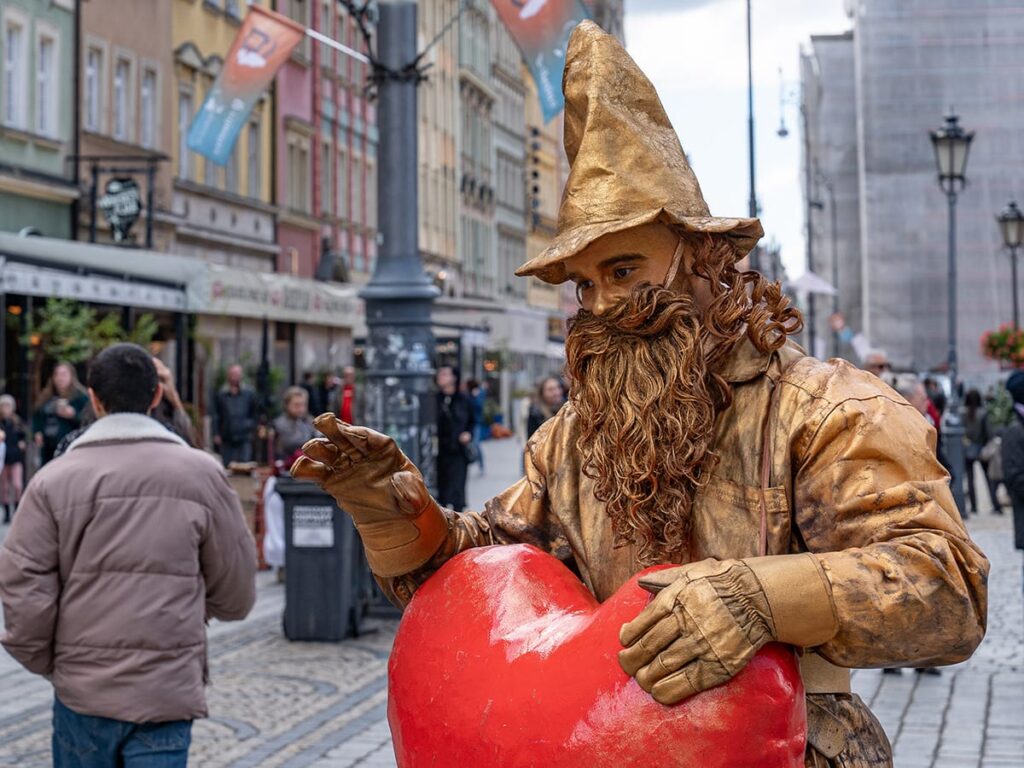 Blick aus dem Restaurantfenster auf eine lebende Statue mit rotem Herz auf dem Marktplatz in Breslau