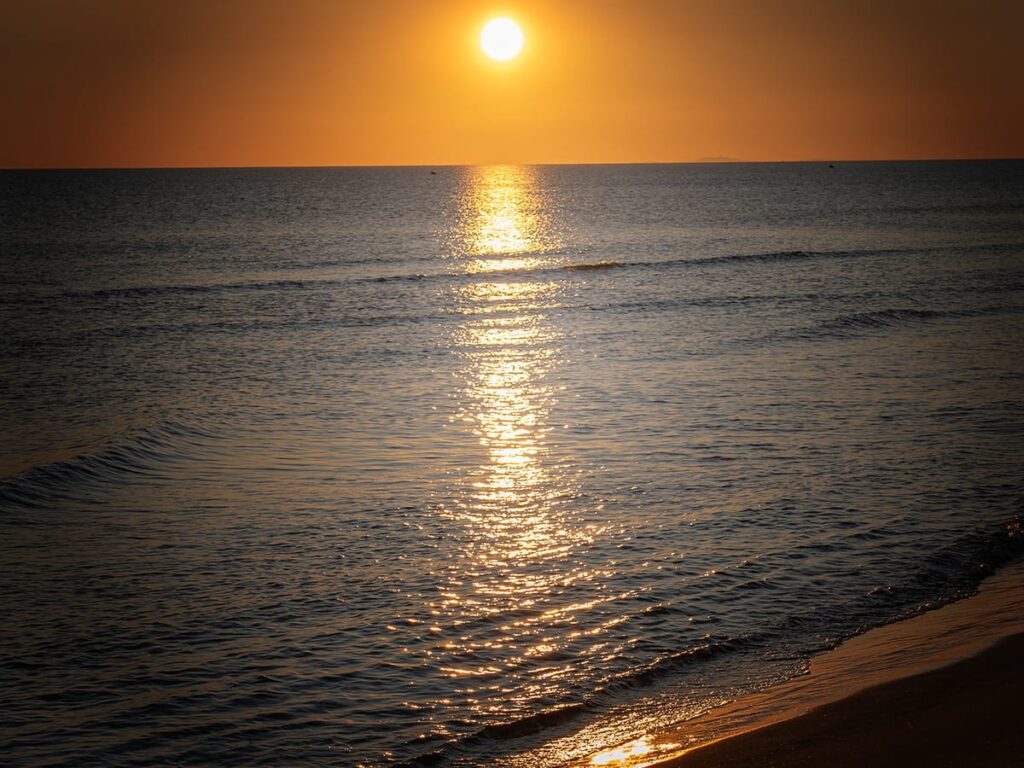 Sonnenuntergang über dem Meer mit goldener Spiegelung auf dem Wasser.
