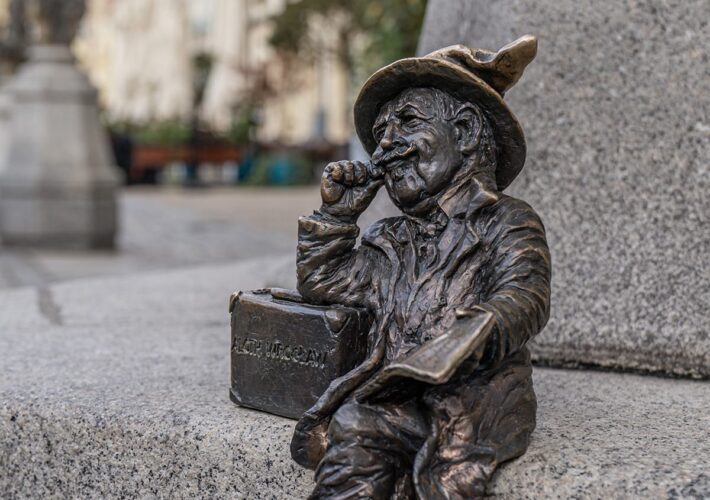 Bronzener Zwerg sitzt lesend auf einer Steinbank in der Altstadt von Breslau