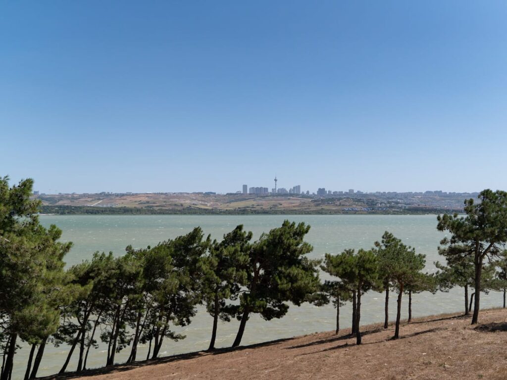 Panoramablick über den Büyüçekmece-See mit Pinien am Ufer und der Skyline auf der anderen Seite