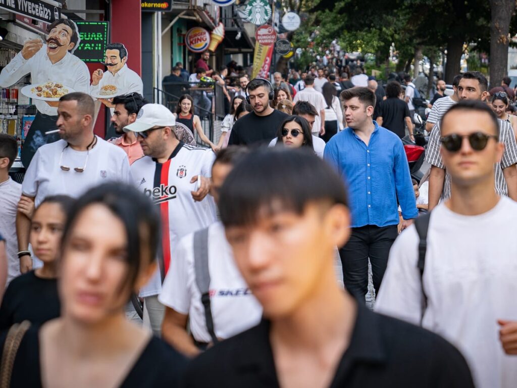 Dichte Menschenmenge in einer belebten Einkaufsstraße in Istanbul mit Burger-King-Schild im Hintergrund.