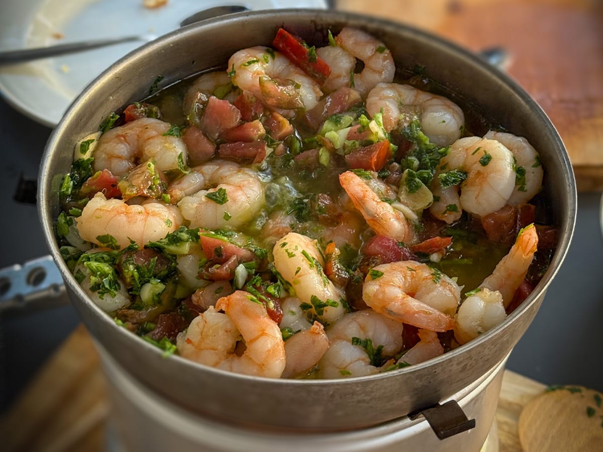 Garnelen in Olivenöl mit Knoblauch und Tomaten in einer Pfanne auf dem Campingkocher
