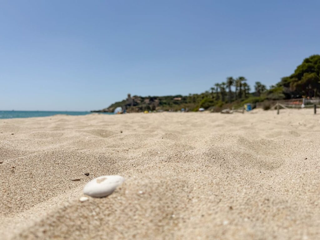 Sanddetail am Playa Tamarit mit unscharfem Castell de Tamarit im Hintergrund an der Costa Dorada