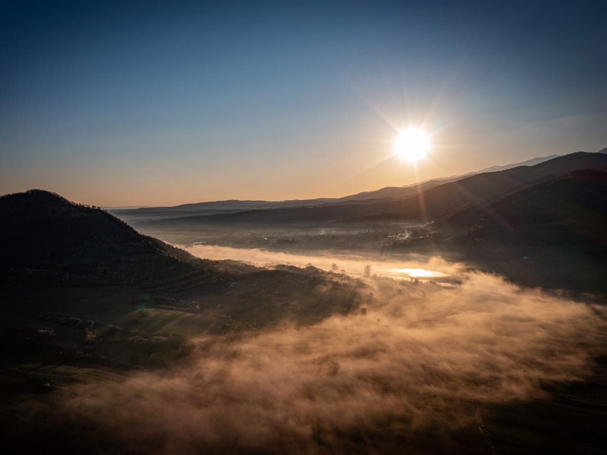 Sonnenaufgang über einem nebelverhangenen Tal bei Boița in Rumänien aus der Luft