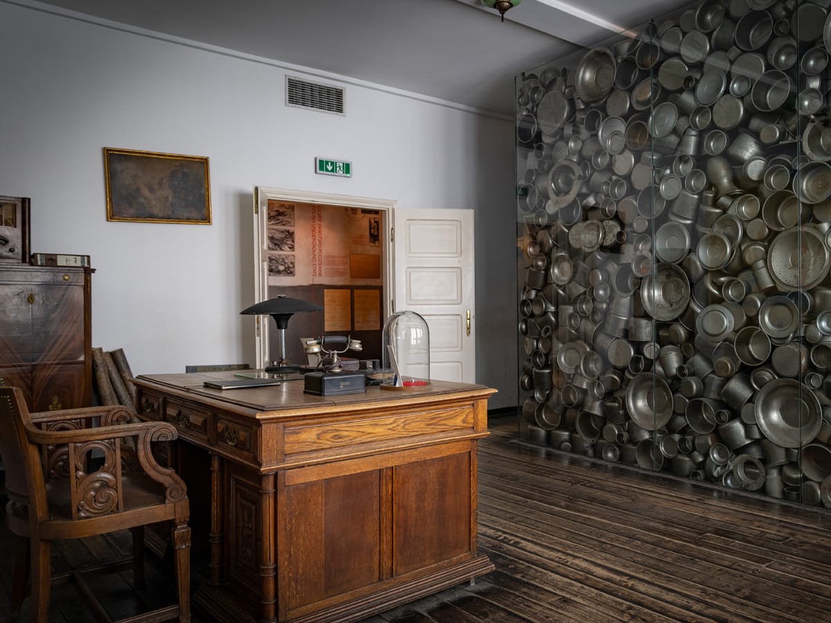 Büro im Schindler Museum Krakau mit Schreibtisch und Glascube voller Emaille-Geschirr