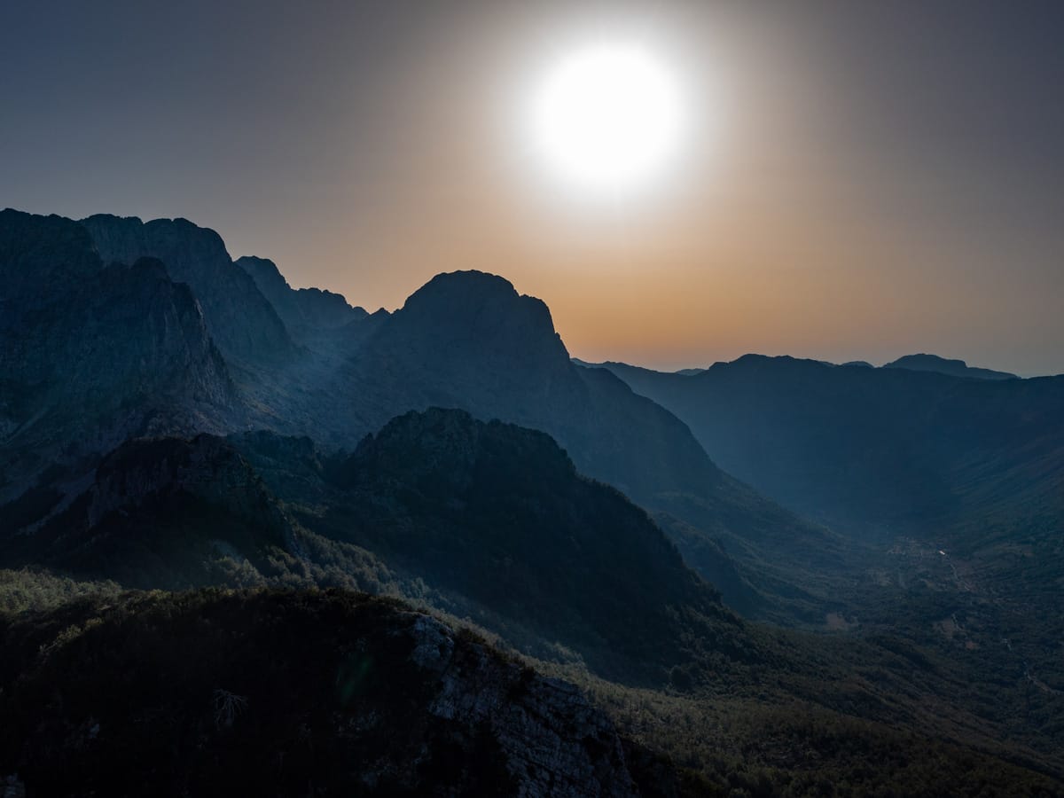 Luftaufnahme der Albanischen Alpen bei Theth im Morgenlicht mit aufgehender Sonne über den Bergen