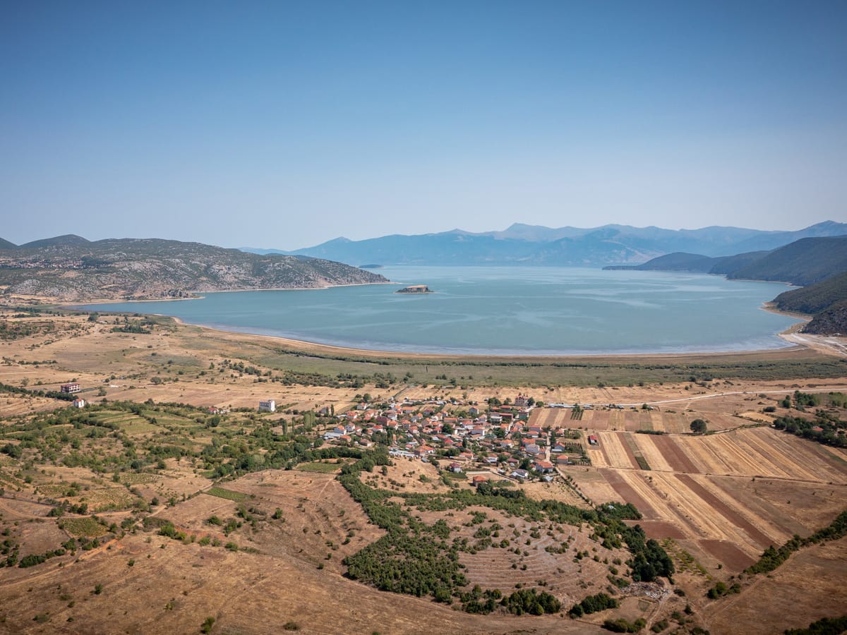 Luftaufnahme von Pustec am Prespasee in Albanien mit Dorf, Feldern und See