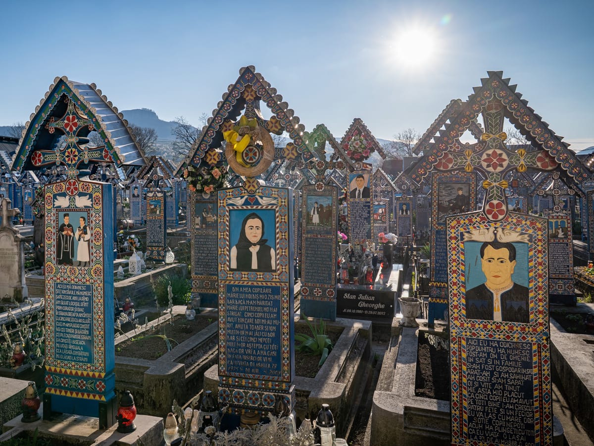 Bunte Holzkreuze auf dem fröhlichen Friedhof in Săpânța im Gegenlicht der Sonne
