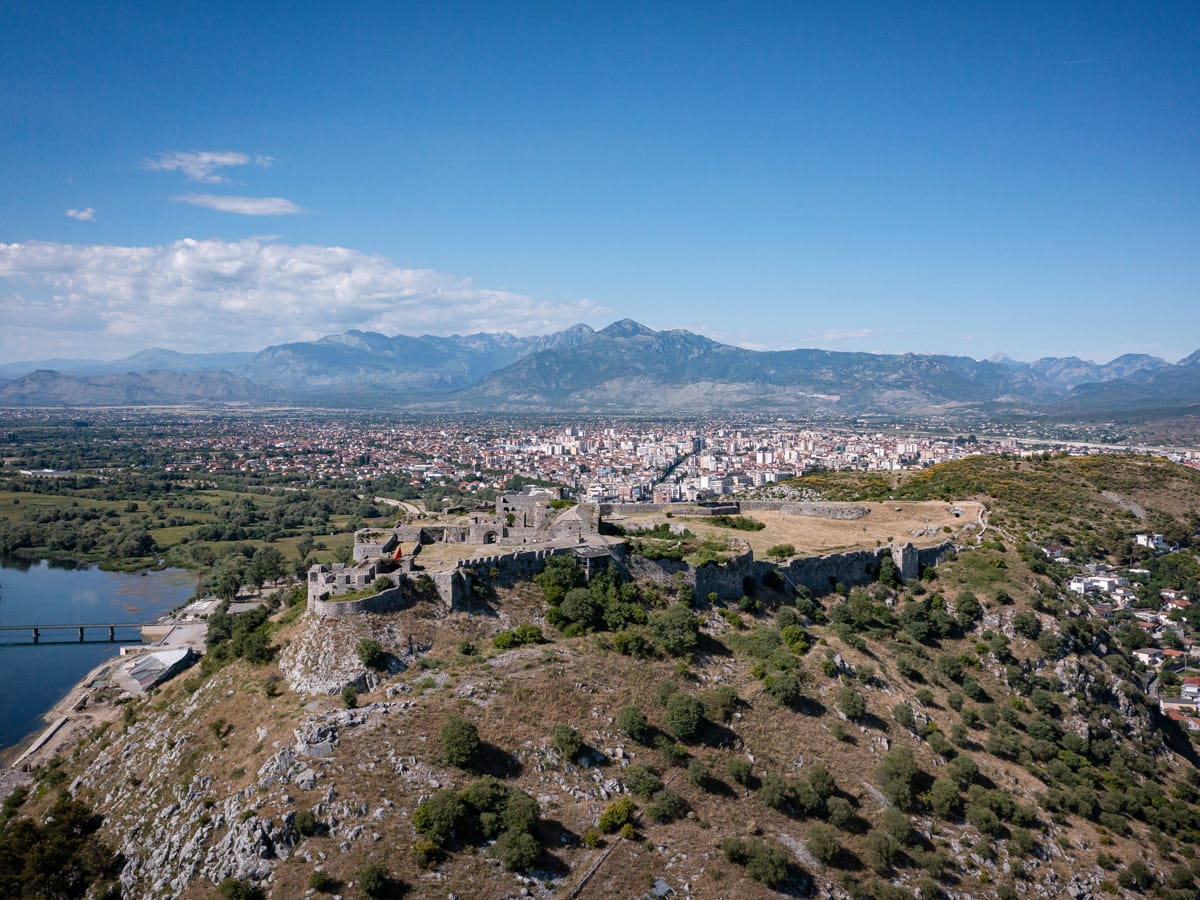 Luftaufnahme der Burg Rozafa oberhalb von Shkodra mit Blick auf die Stadt und die albanischen Alpen im Hintergrund.