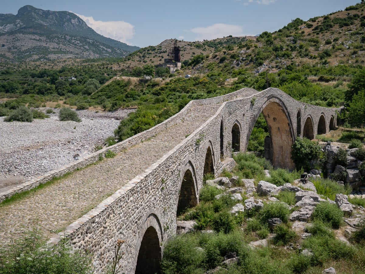 Historische osmanische Mes-Brücke bei Postribë in Nordalbanien mit ihren charakteristischen Steinbögen über dem Flussbett.