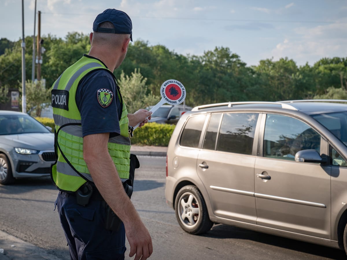 Polizist mit roter Verkehrskelle regelt den Verkehr an einem Kreisverkehr in Shkodra in Albanien.