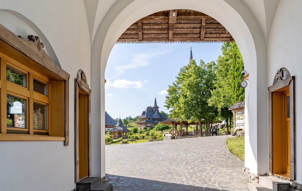 Blick durch das Eingangstor des Klosters Bârsana auf die Holzkirchen und Gebäude der Klosteranlage in der Maramureș.