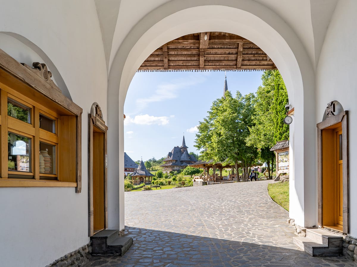 Blick durch das Eingangstor des Klosters Bârsana auf die Holzkirchen und Gebäude der Klosteranlage in der Maramureș.