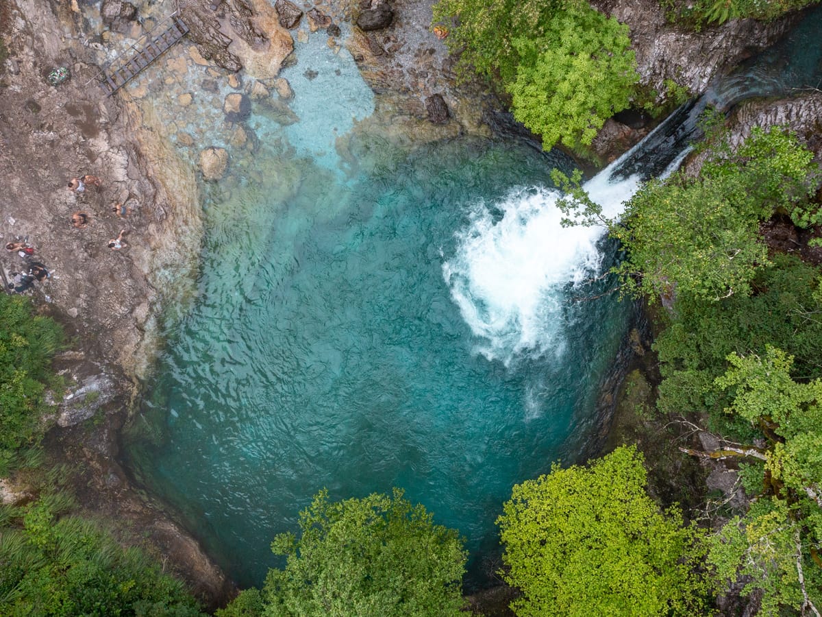 Drohnenaufnahme des Blue Eye mit Wasserfall und türkisfarbenem Quelltopf bei Nderlysaj in Albanien.