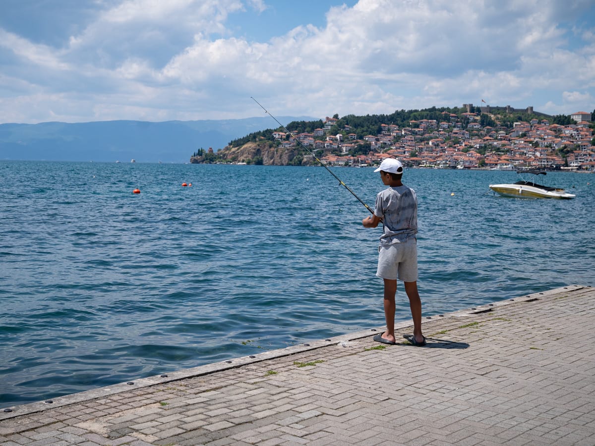 Junge angelt am Ufer des Ohridsees vor der Altstadt von Ohrid