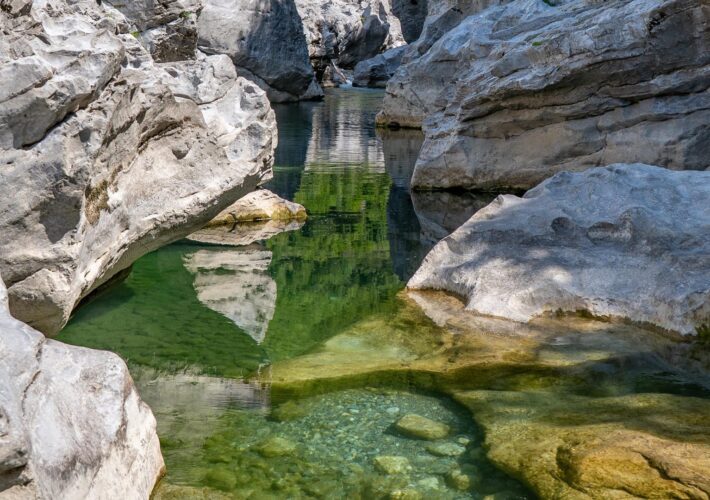 Kristallklarer Naturpool mit smaragdgrünem Gebirgswasser zwischen hellen Kalksteinfelsen am Kir-Fluss bei Prekal nahe Shkodra.