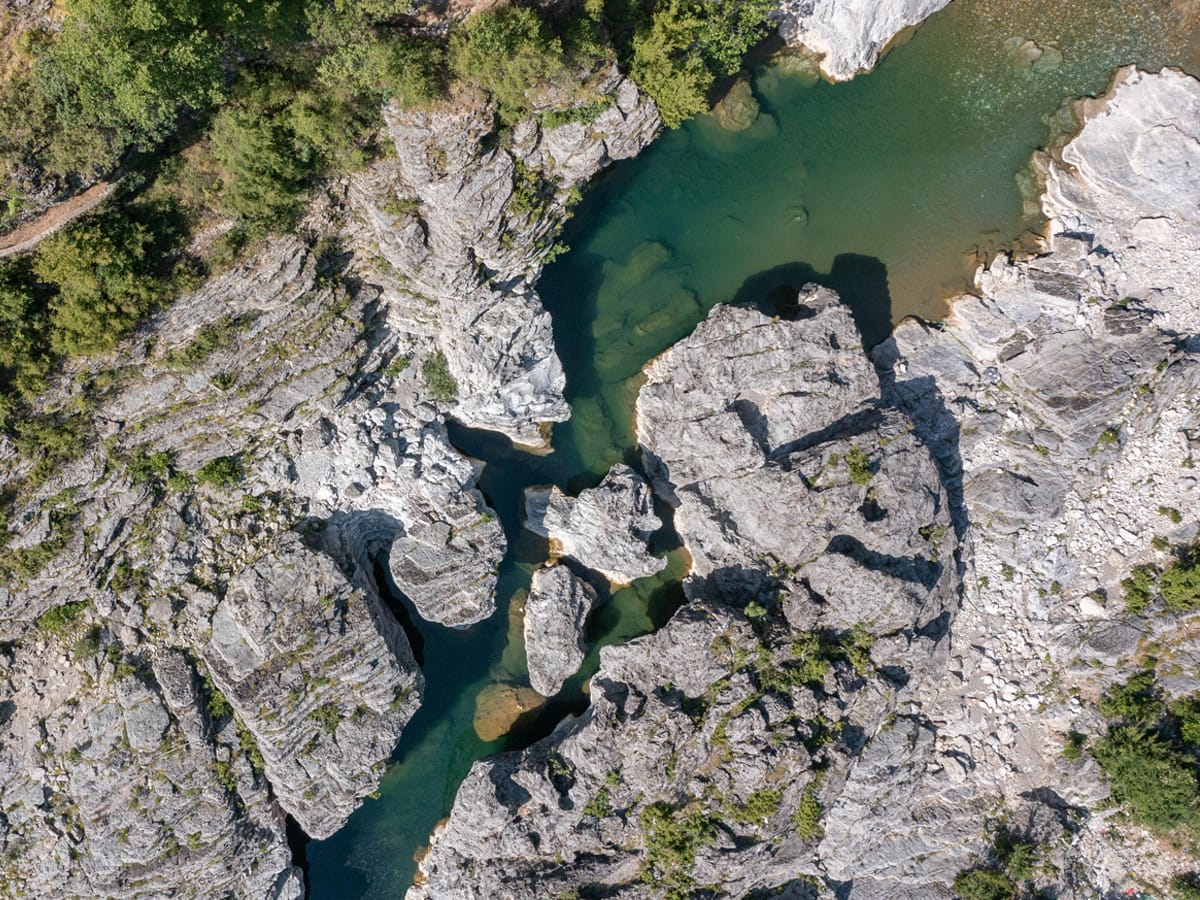 Drohnenaufnahme einer natürlichen Schlucht des Kir-Flusses bei Prekal mit kristallklarem, smaragdgrünem Gebirgswasser zwischen hellen Kalksteinfelsen.