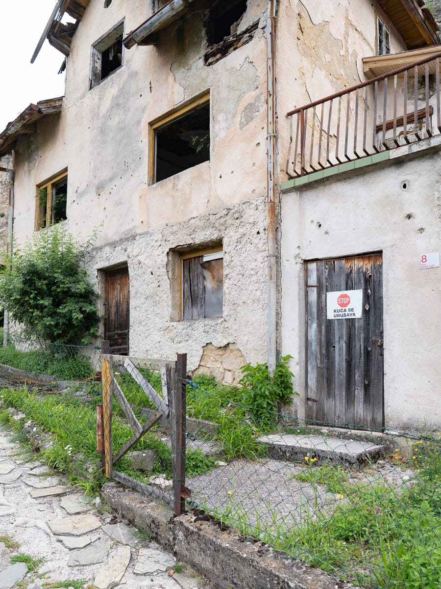 Verlassenes Wohnhaus mit Einschusslöchern und Warnschild in der Altstadt von Jajce, Bosnien-Herzegowina.