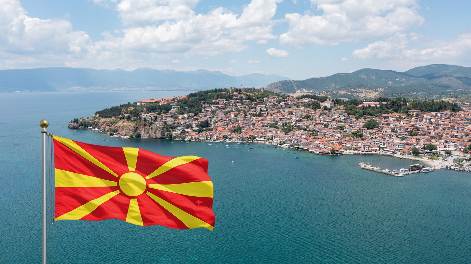 Drohnenaufnahme der Altstadt von Ohrid am Ohridsee mit der Flagge Nordmazedoniens im Vordergrund.