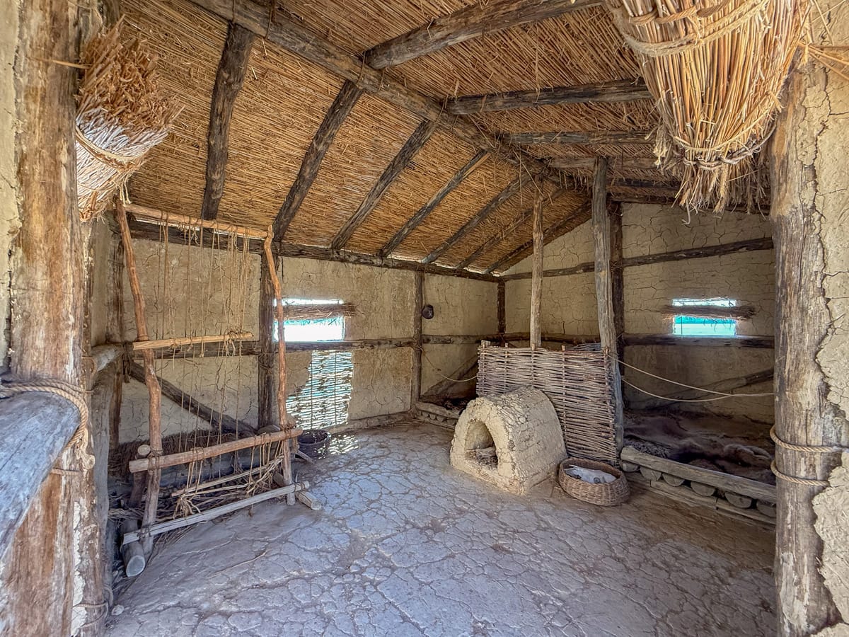 Innenraum eines rekonstruierten Pfahlbauhauses in der Museumsbucht der Knochen am Ohridsee mit Feuerstelle und Schlafplätzen.