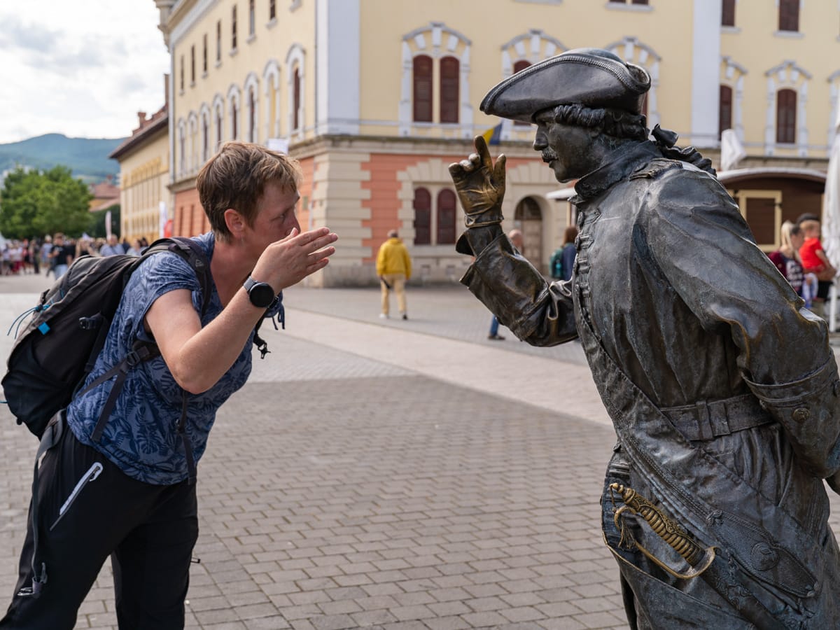 Besucherin im Gespräch mit einer historischen Bronzestatue in der Festung Alba Carolina in Alba Iulia.