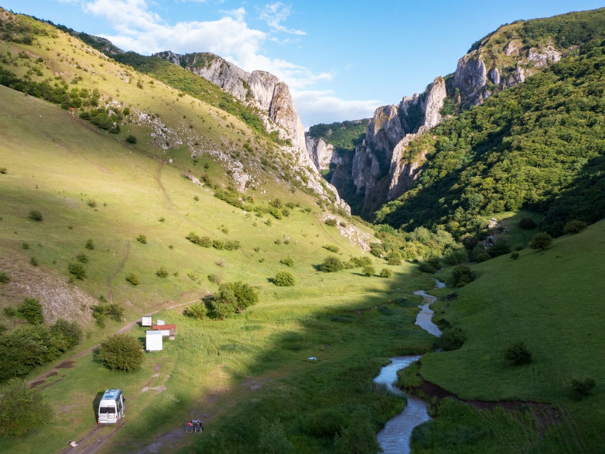 Luftaufnahme der Cheile Turzii mit Wohnmobil, Bachlauf und dem Eingang zur imposanten Kalksteinschlucht in Siebenbürgen.