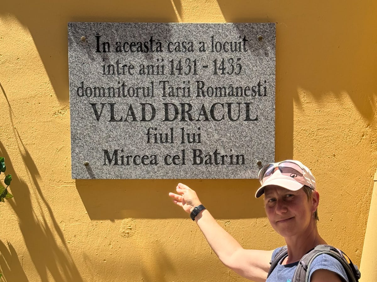 Dani zeigt auf Gedenktafel am historischen Geburtshaus von Vlad Dracul in Schäßburg.