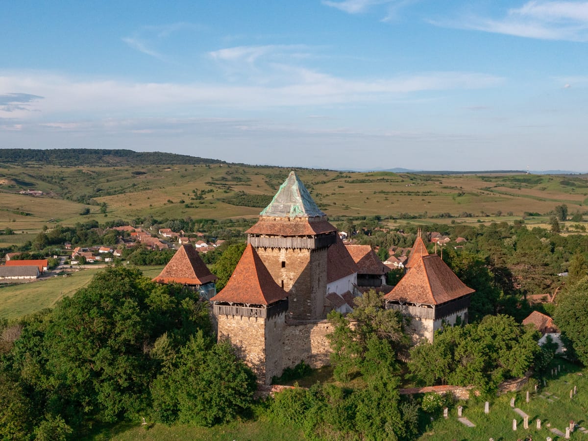 Drohnenaufnahme der Kirchenburg Deutsch-Weißkirch (Viscri) in Siebenbürgen mit dem historischen Dorf und der typischen Hügellandschaft.