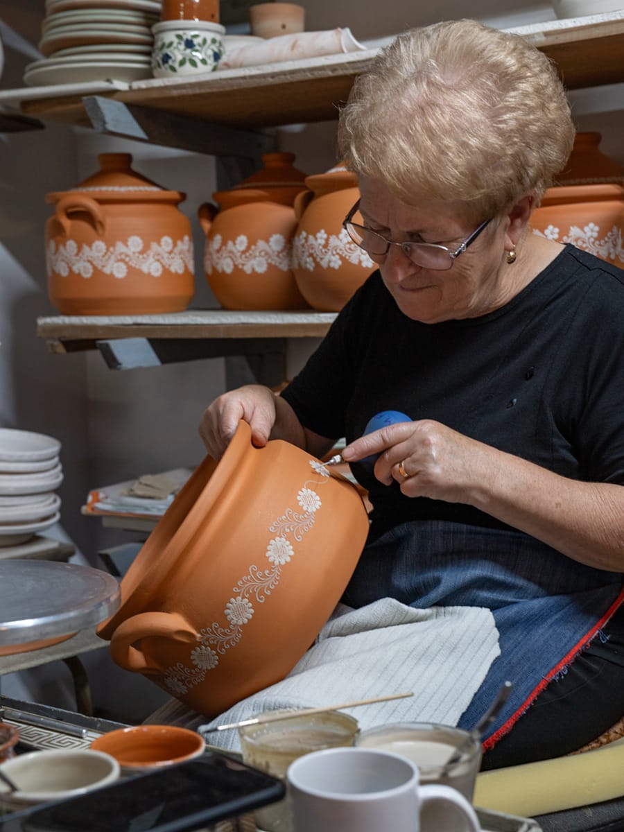 Eine Kunsthandwerkerin verziert in einer Werkstatt in Korund traditionelle rumänische Keramik von Hand.