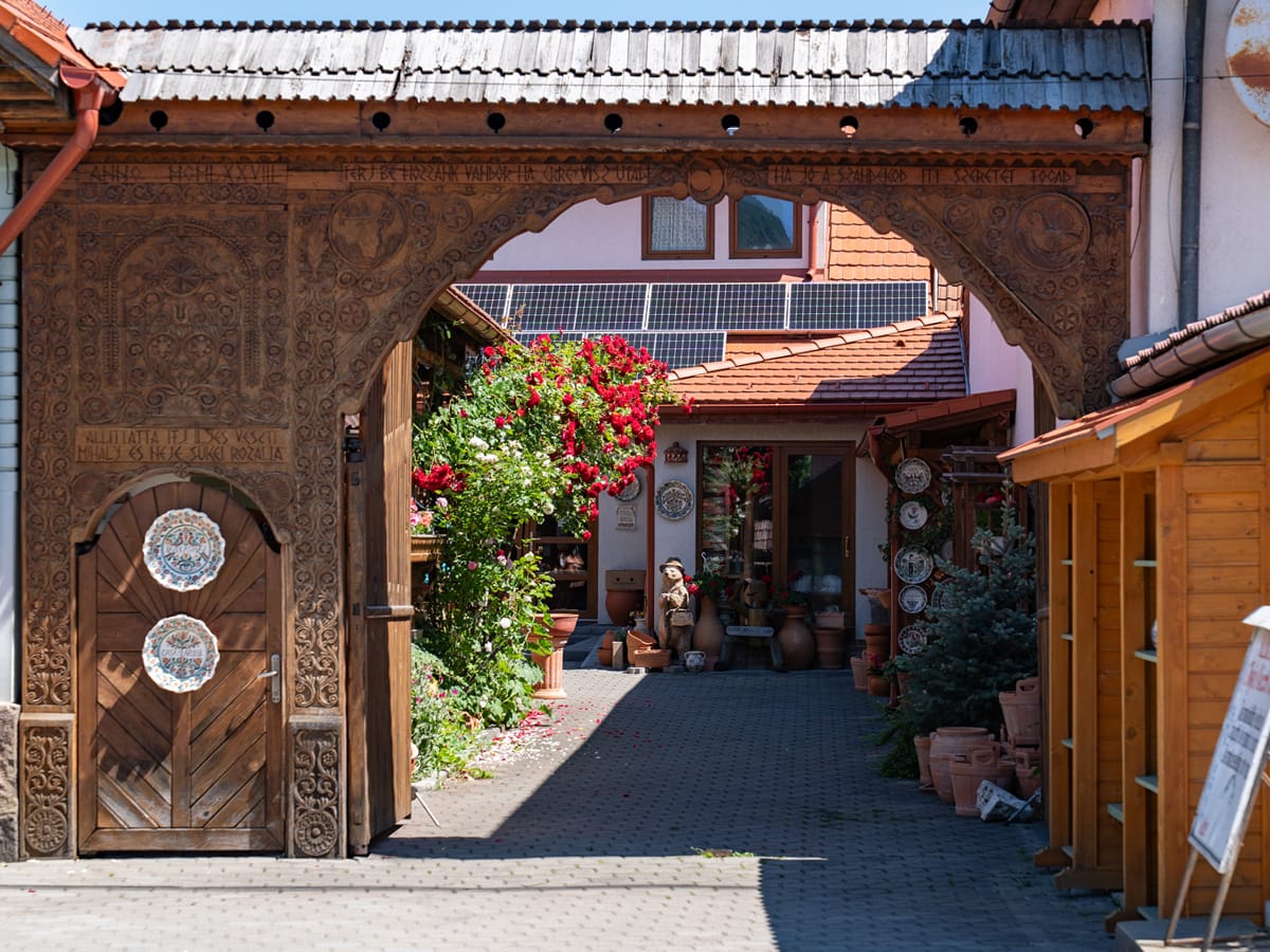 Kunstvoll geschnitztes Holztor einer traditionellen Keramikwerkstatt in Corund (Korund), Siebenbürgen.