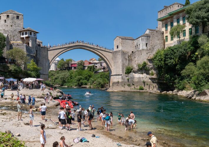 Stari Most in Mostar über der Neretva mit Besuchern am Flussufer