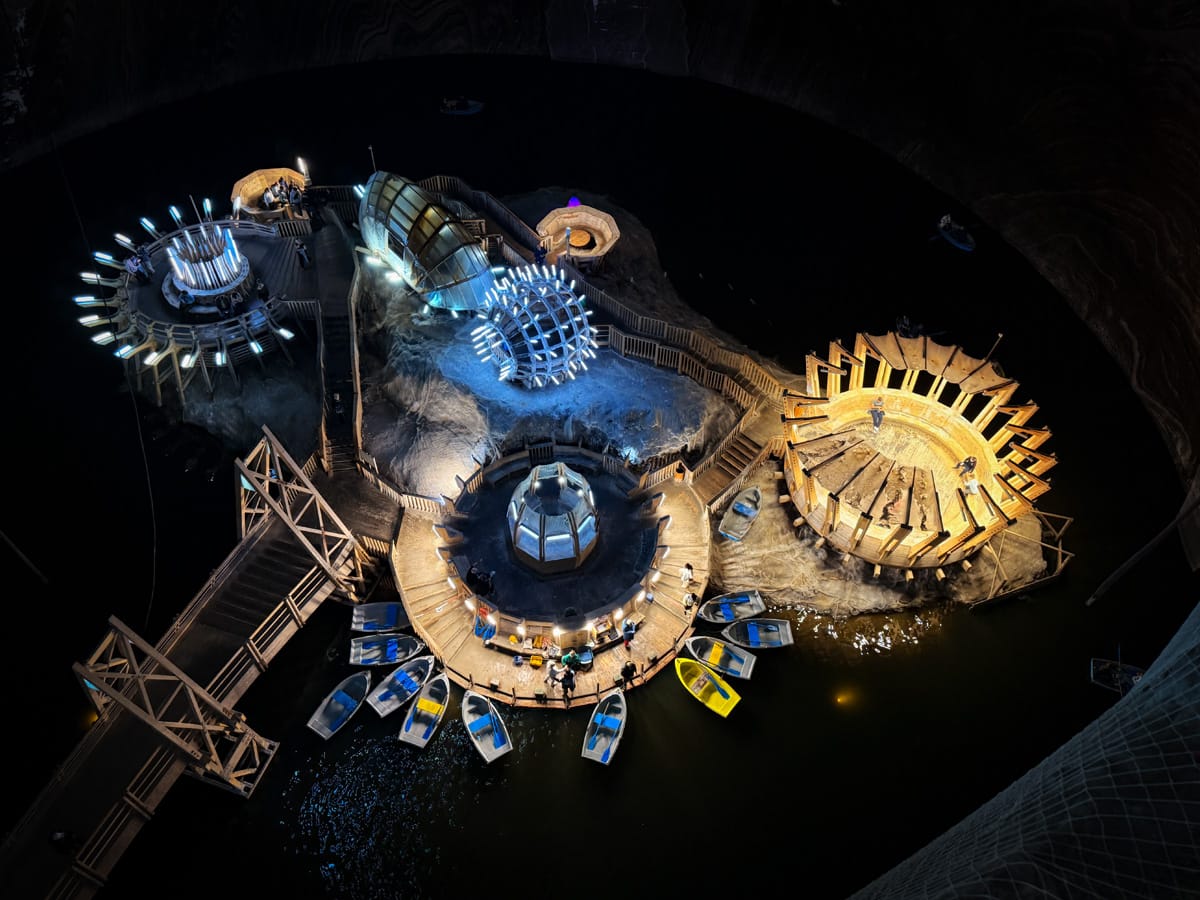 Blick auf den unterirdischen Salzsee der Salina Turda mit Booten, Lichtinstallationen und futuristischen Plattformen.