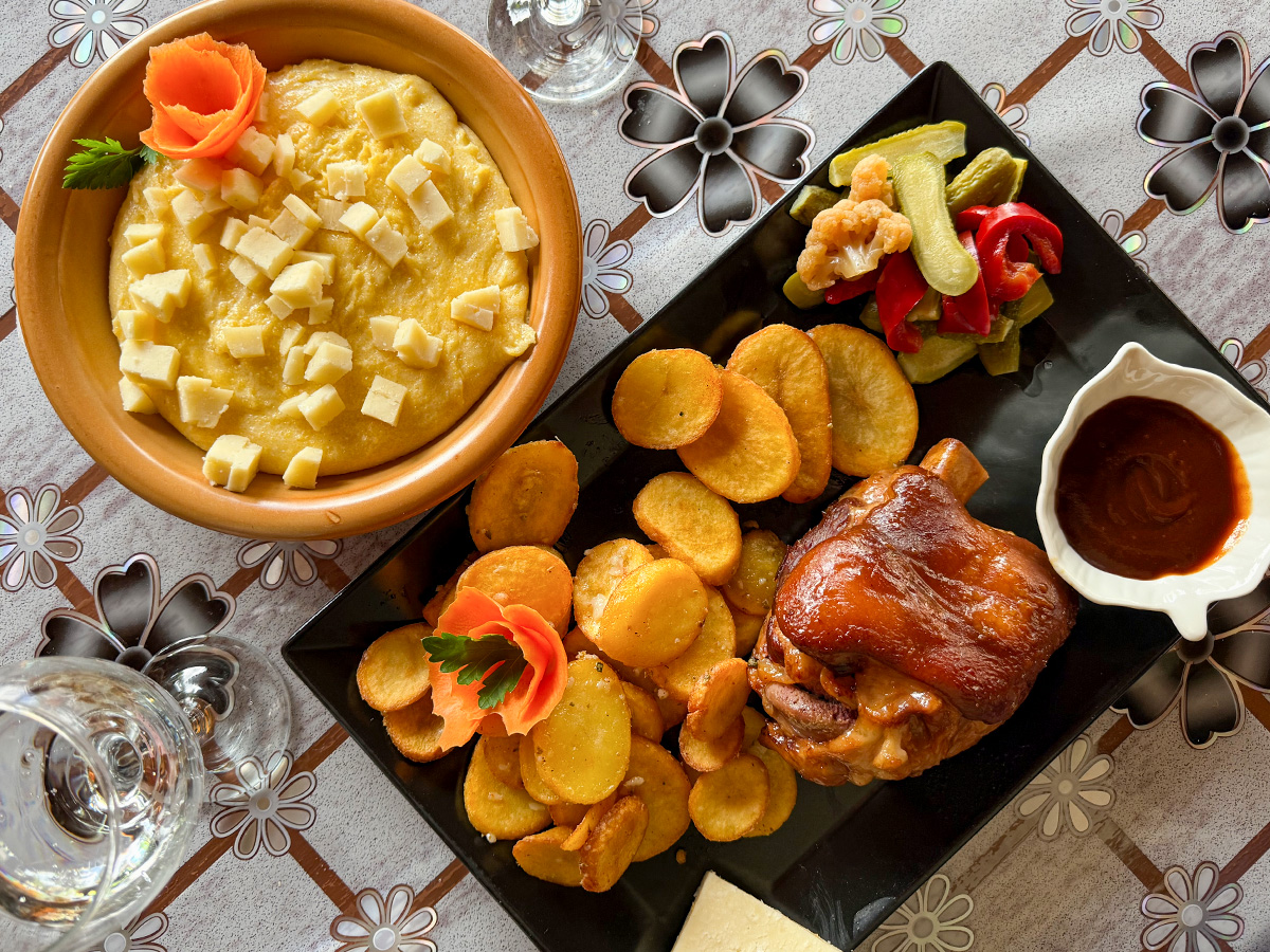 Traditionelle rumänische Schweinshaxe mit Bratkartoffeln und Balmoș im Restaurant Orizont in Farcașa