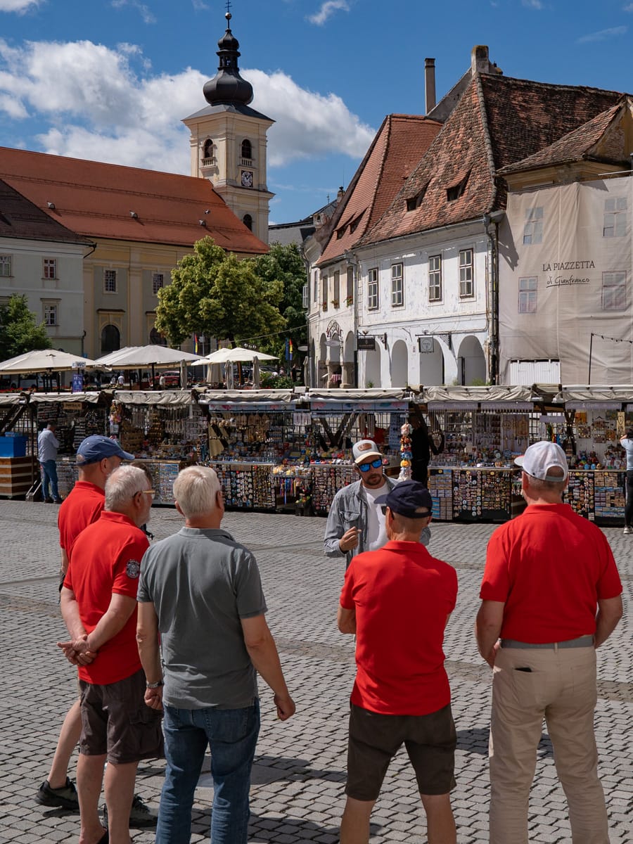 Deutschsprachiger Stadtführer Cristian erklärt einer kleinen Reisegruppe die Altstadt von Sibiu in Rumänien.