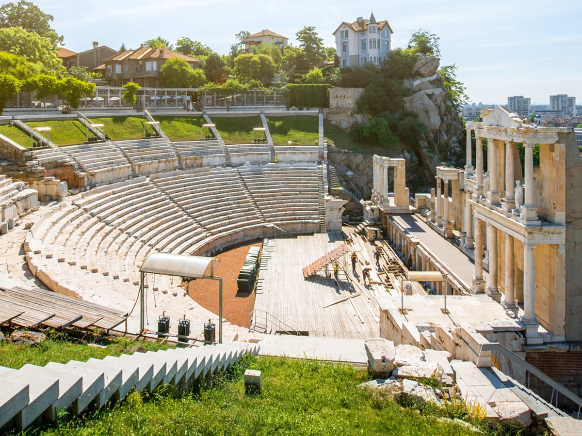 Antikes Theater von Plowdiw mit halbkreisförmigen Sitzreihen, einer säulengeschmückten Bühnenfassade und Stadtblick im Hintergrund.